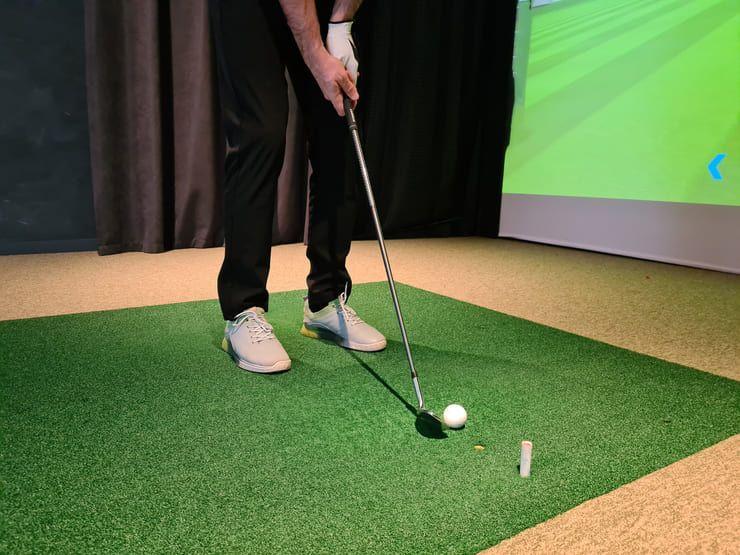 Golfer hitting a short iron on an indoor golf simulator